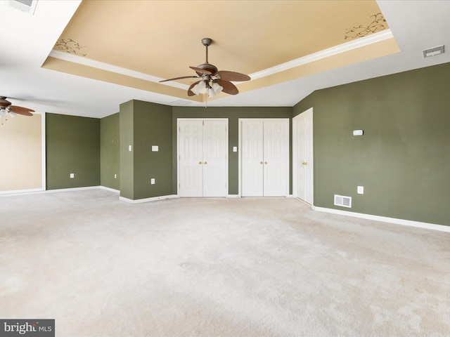 carpeted spare room with ornamental molding, a tray ceiling, and ceiling fan