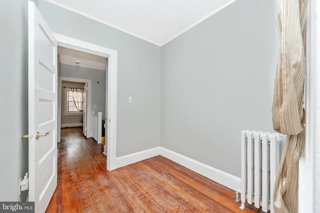 hallway with radiator, wood-type flooring, and ornamental molding