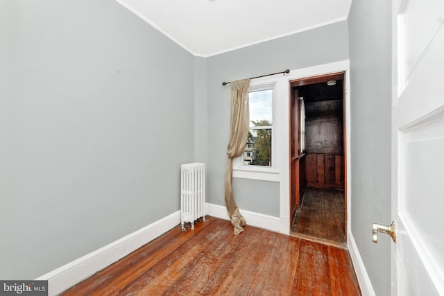 unfurnished room featuring hardwood / wood-style floors, radiator heating unit, and crown molding