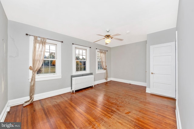 empty room featuring radiator, hardwood / wood-style flooring, and ceiling fan