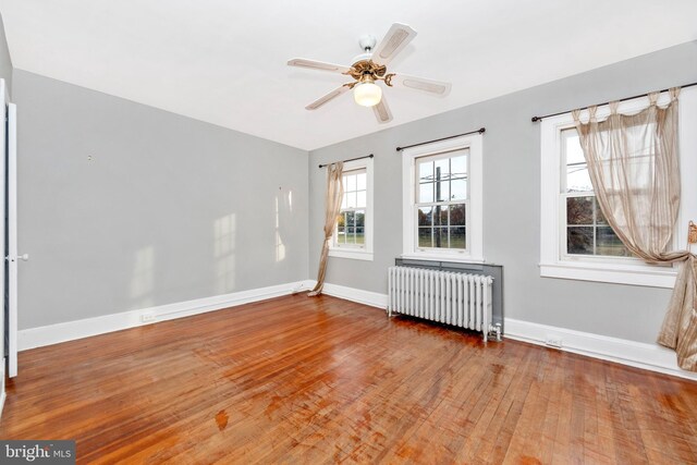 unfurnished room with radiator, wood-type flooring, and ceiling fan