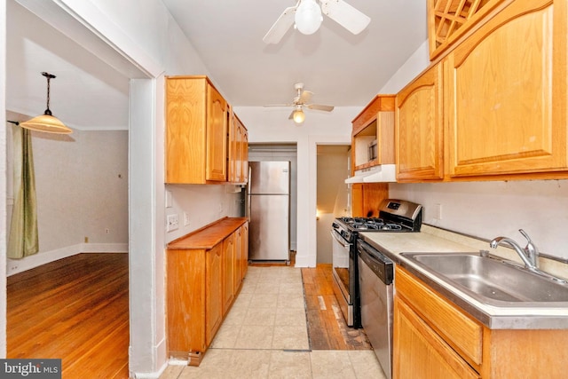 kitchen with stainless steel appliances, light hardwood / wood-style floors, sink, ventilation hood, and pendant lighting