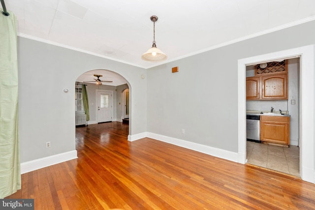 empty room featuring ornamental molding, radiator, hardwood / wood-style floors, and ceiling fan