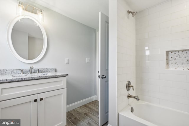 bathroom with hardwood / wood-style floors, tiled shower / bath combo, and vanity