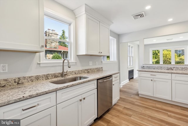 kitchen with visible vents, light wood-style flooring, stainless steel dishwasher, white cabinetry, and a sink