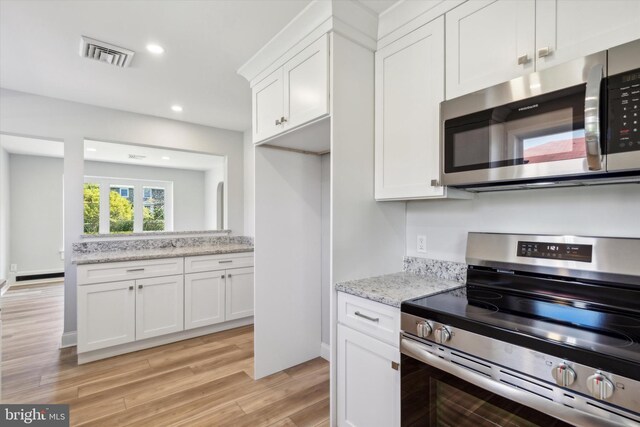 kitchen featuring white cabinetry, light hardwood / wood-style floors, light stone countertops, and stainless steel appliances