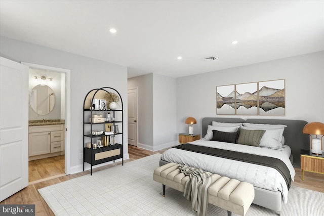 bedroom featuring light hardwood / wood-style floors, sink, and connected bathroom