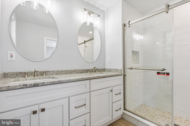 bathroom featuring a shower with door and vanity