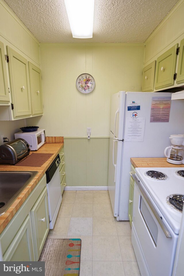 kitchen featuring a textured ceiling, green cabinetry, light tile patterned floors, and white appliances