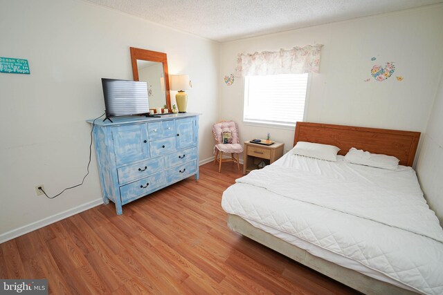 bedroom featuring light hardwood / wood-style flooring and a textured ceiling