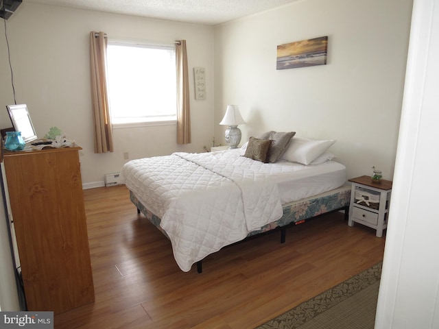 bedroom featuring dark wood-type flooring, a baseboard radiator, and a textured ceiling