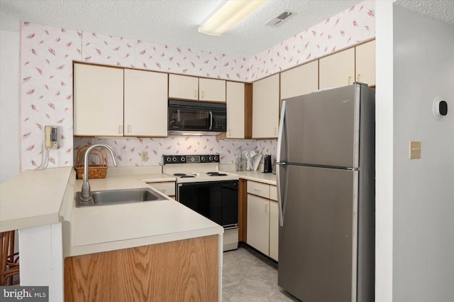 kitchen with black microwave, light countertops, white range with electric stovetop, freestanding refrigerator, and wallpapered walls