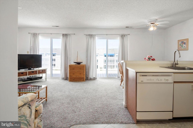 kitchen featuring light countertops, white dishwasher, a sink, and a healthy amount of sunlight