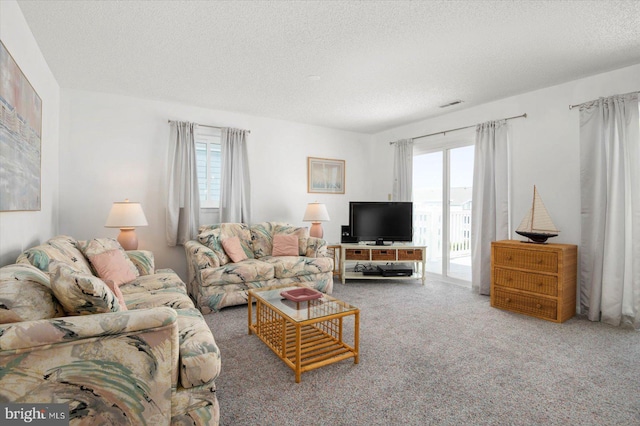 living area with a textured ceiling, visible vents, and carpet flooring