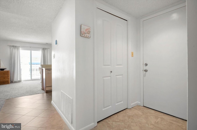 corridor with light colored carpet and a textured ceiling