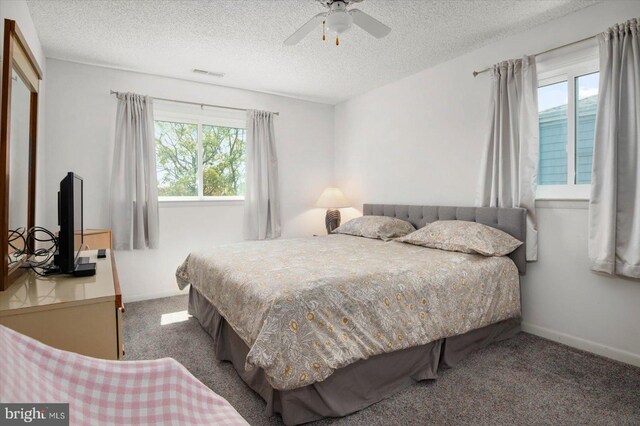 carpeted bedroom with a ceiling fan, visible vents, a textured ceiling, and baseboards