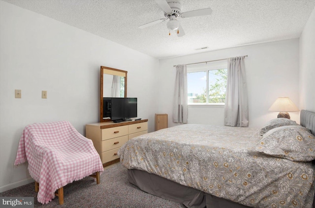 carpeted bedroom featuring ceiling fan and a textured ceiling