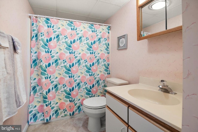 bathroom with a paneled ceiling, a textured wall, vanity, and toilet