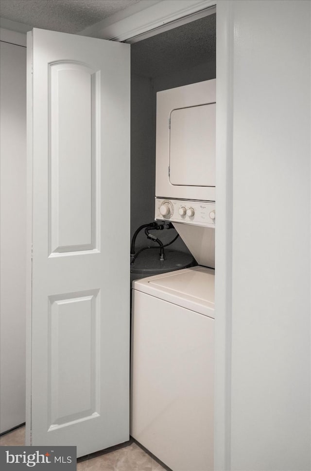 washroom featuring stacked washer and dryer and light tile patterned floors