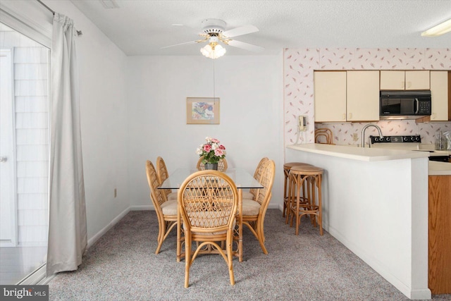 dining room featuring light carpet, a ceiling fan, baseboards, and a textured ceiling