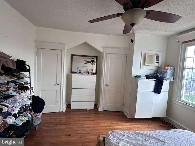 bedroom with a textured ceiling, ceiling fan, hardwood / wood-style floors, and a wall mounted AC