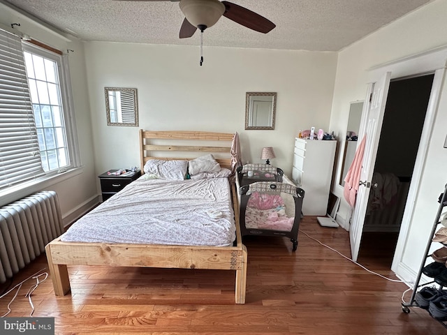 bedroom featuring ceiling fan, wood-type flooring, a textured ceiling, and radiator