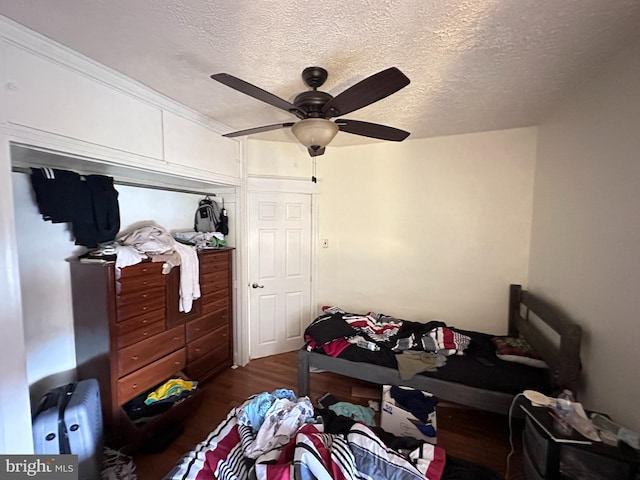 bedroom with a textured ceiling, ceiling fan, and dark hardwood / wood-style flooring