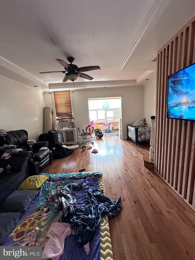 living room featuring hardwood / wood-style floors, a raised ceiling, ornamental molding, and ceiling fan