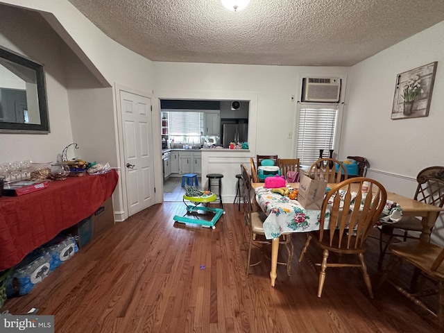 dining room featuring hardwood / wood-style flooring, a textured ceiling, and an AC wall unit