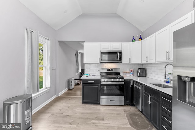 kitchen with appliances with stainless steel finishes, light hardwood / wood-style flooring, decorative backsplash, and a healthy amount of sunlight