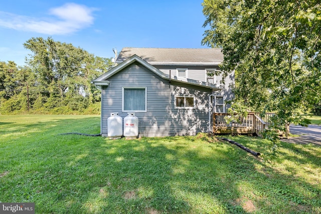 back of property with a deck and a lawn