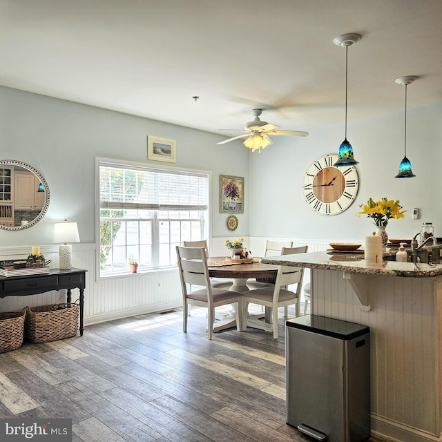 dining area featuring ceiling fan, wood finished floors, and wainscoting