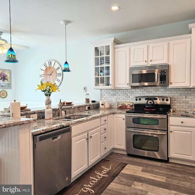 kitchen with white cabinetry, appliances with stainless steel finishes, hanging light fixtures, and dark wood-type flooring