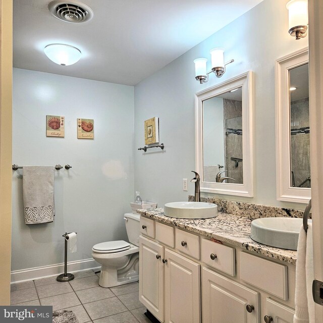 bathroom with toilet, double vanity, and tile patterned flooring