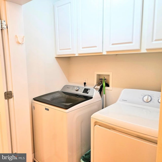 clothes washing area featuring cabinets and washer and clothes dryer