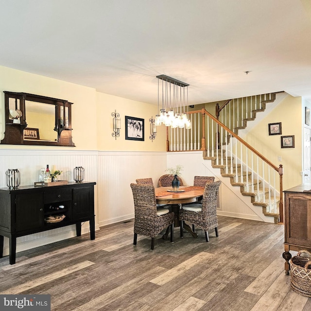 dining area featuring stairs, a wainscoted wall, and wood finished floors