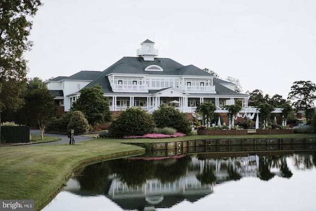 back of house featuring a water view, a lawn, a balcony, and a pergola