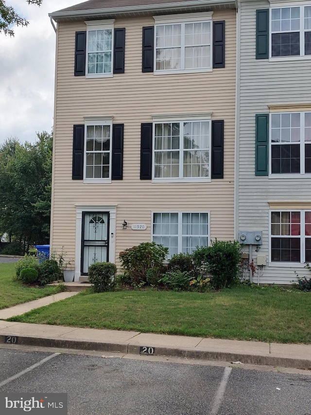 townhome / multi-family property with uncovered parking and a front lawn