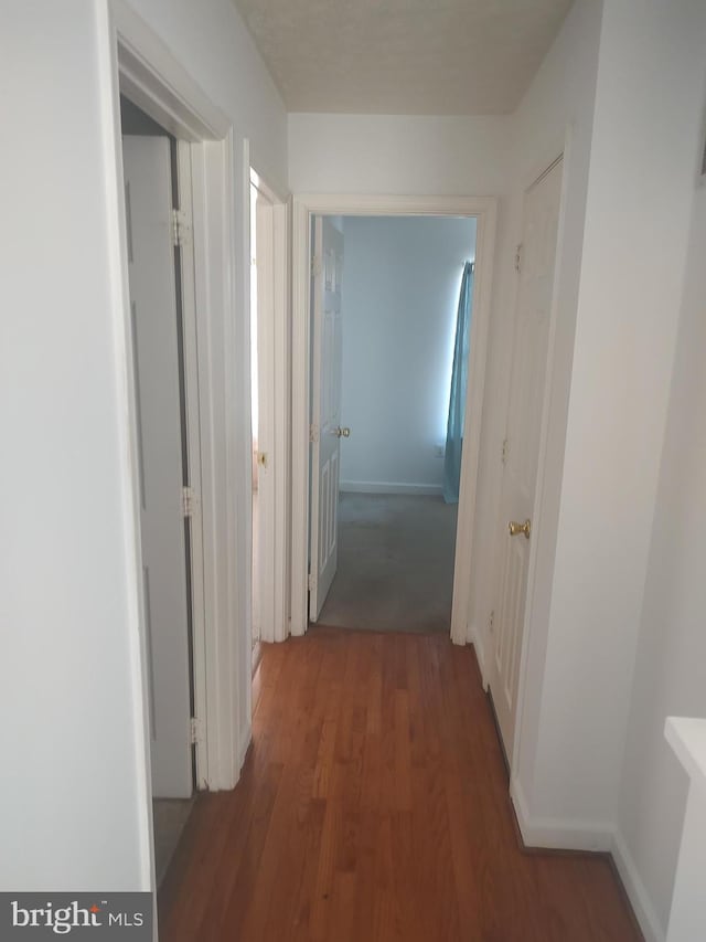 corridor with wood finished floors and baseboards