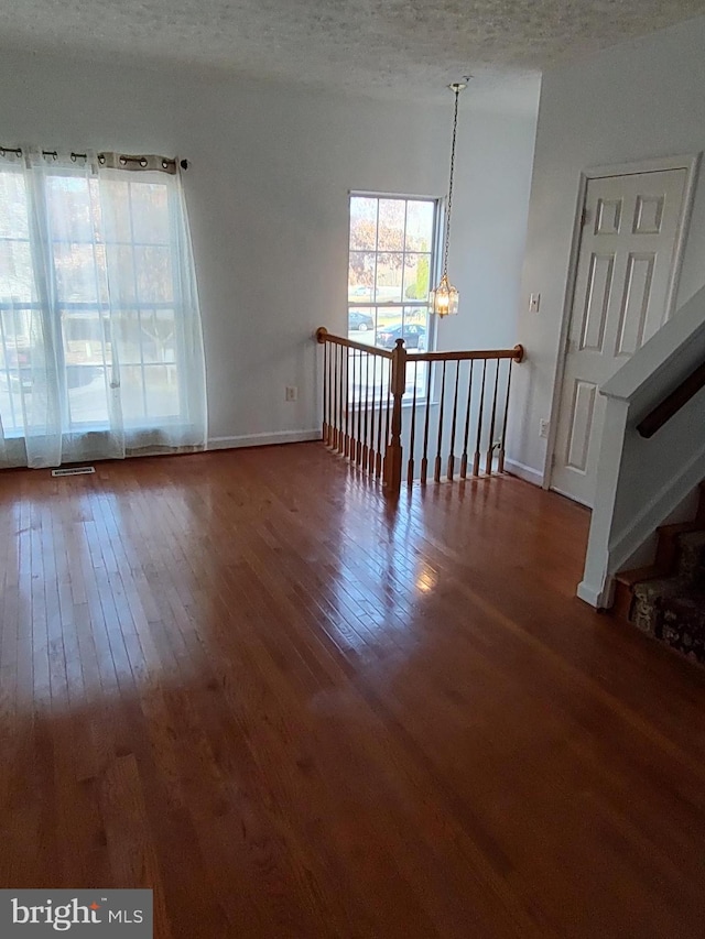 spare room featuring a chandelier, a textured ceiling, and hardwood / wood-style flooring