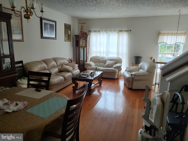 living room featuring a chandelier, a textured ceiling, and wood-type flooring