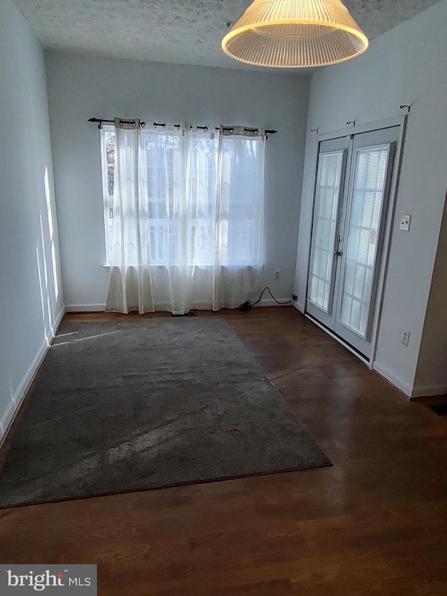 spare room featuring a textured ceiling, french doors, wood finished floors, and baseboards