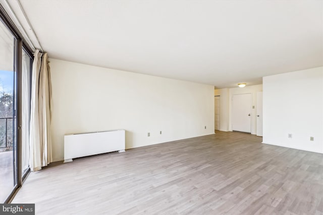 unfurnished room with radiator and light wood-type flooring