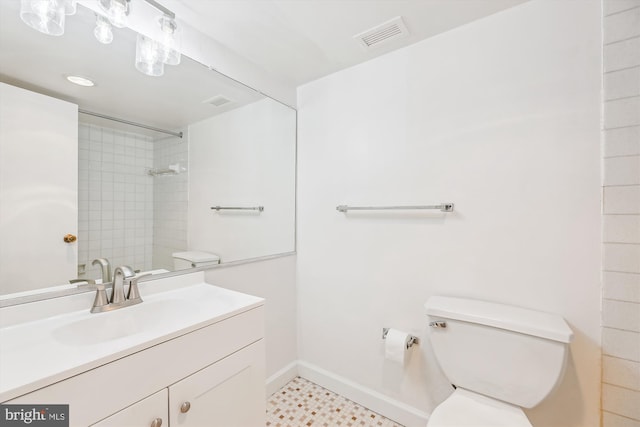 bathroom featuring toilet, vanity, visible vents, baseboards, and walk in shower