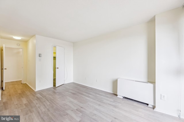 empty room featuring light wood-type flooring and radiator