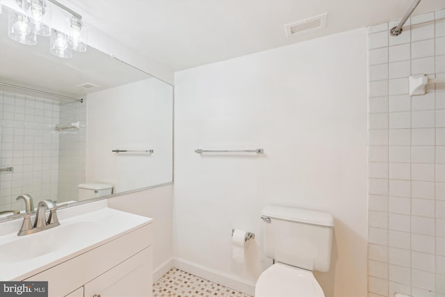 bathroom with baseboards, visible vents, toilet, a tile shower, and vanity