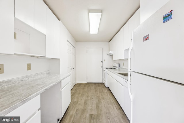 kitchen with white appliances, light countertops, light wood-type flooring, under cabinet range hood, and white cabinetry