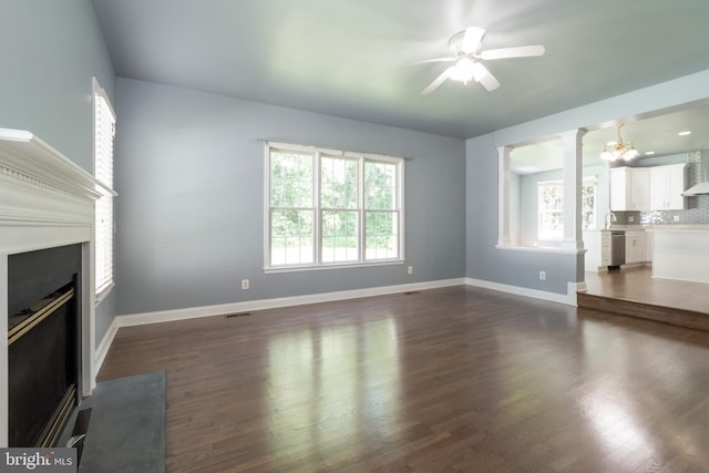 unfurnished living room with ceiling fan, ornate columns, dark wood-type flooring, and sink