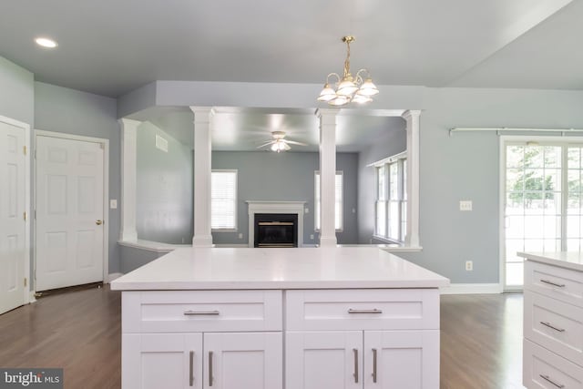 kitchen featuring white cabinetry, dark hardwood / wood-style floors, hanging light fixtures, and decorative columns