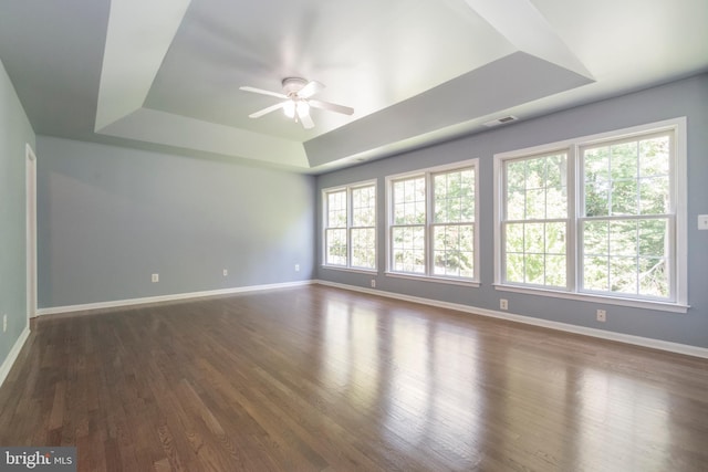 spare room featuring ceiling fan, a tray ceiling, and dark wood-type flooring